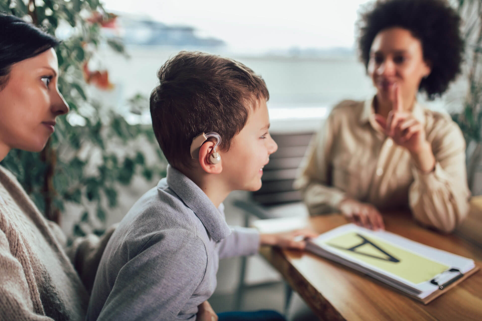 child with hearing aid learning a school lesson with a sign language interpreter