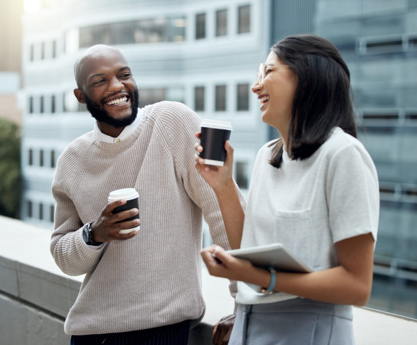 Two businesspeople drinking coffee together outside an office