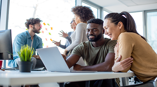A office staff talking and smiling over a laptop
