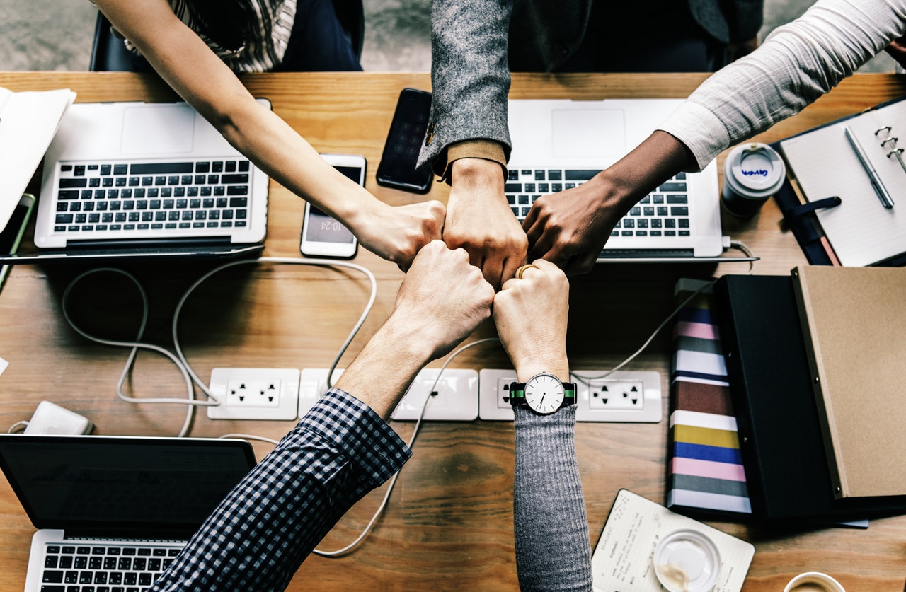Five colleagues fist bump over successful work planning
