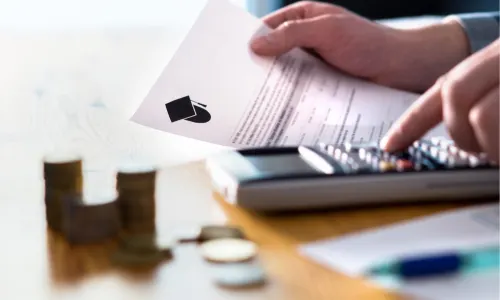 A person using a calculator with a document showing a graduation cap icon and coins nearby.