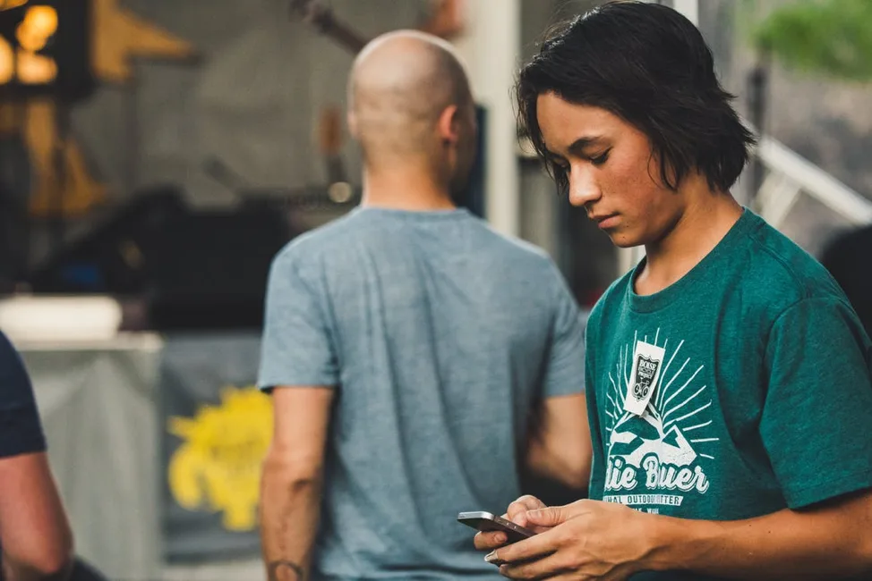 A young person with dark hair looks at their smartphone, representing the Gen Z demographic and their preference for mobile banking.