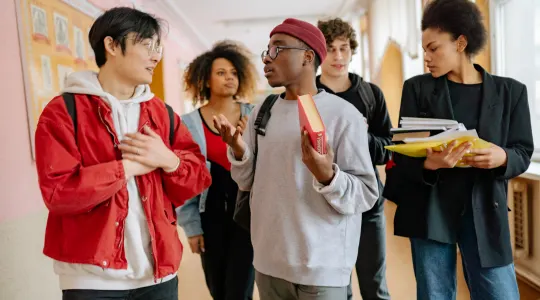 A diverse group of Gen Z students walking and talking in a school hallway, representing the target audience.