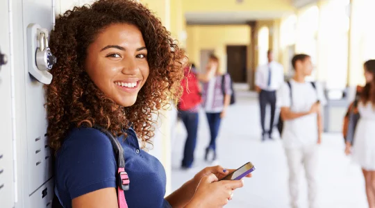 Young woman holding books in school hallway