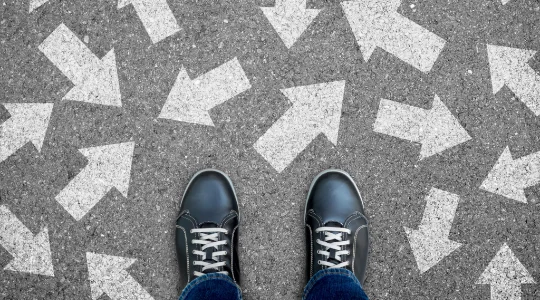 Feet standing before crossroads with many directions