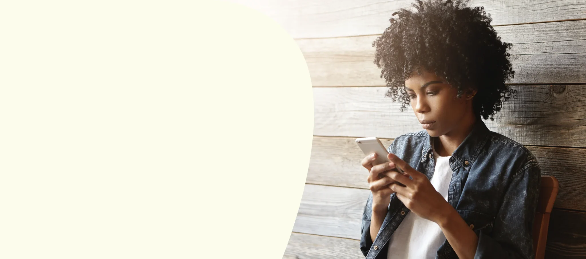 Young woman sitting against all using smartphone