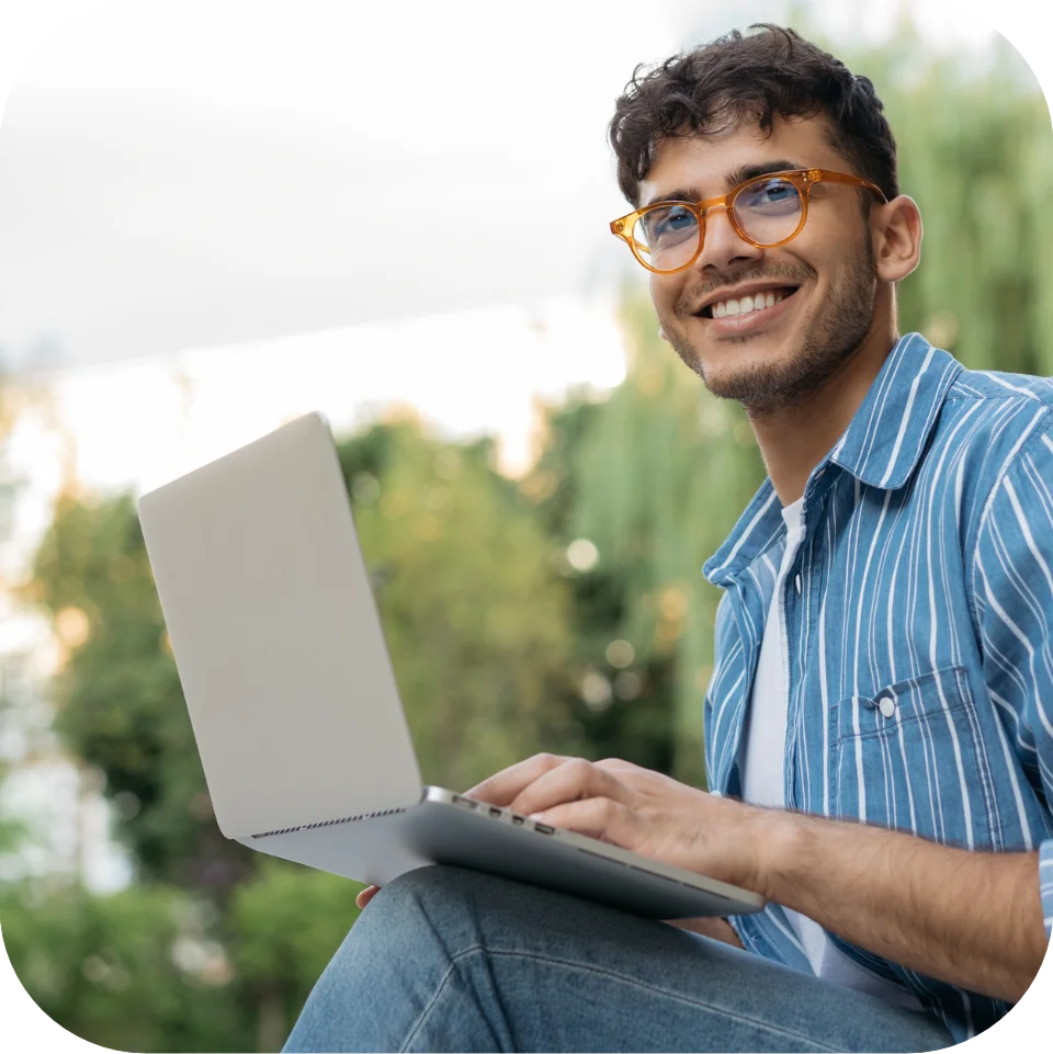 Young man using laptop outside and smiling
