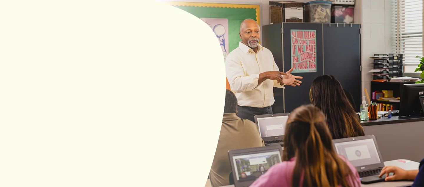 Male teacher presenting to class while students use Everfi courses