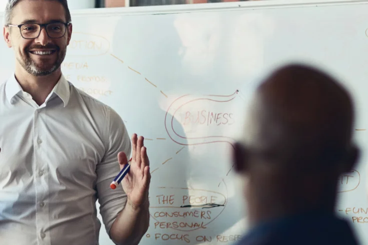 Employee using whiteboard to present to colleague
