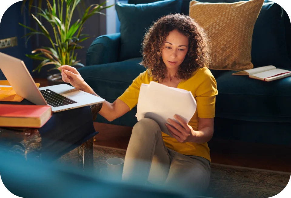 Woman reviewing notes while using laptop