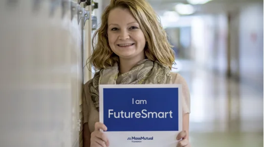 Teacher smiling in hallway while holding FutureSmart sign